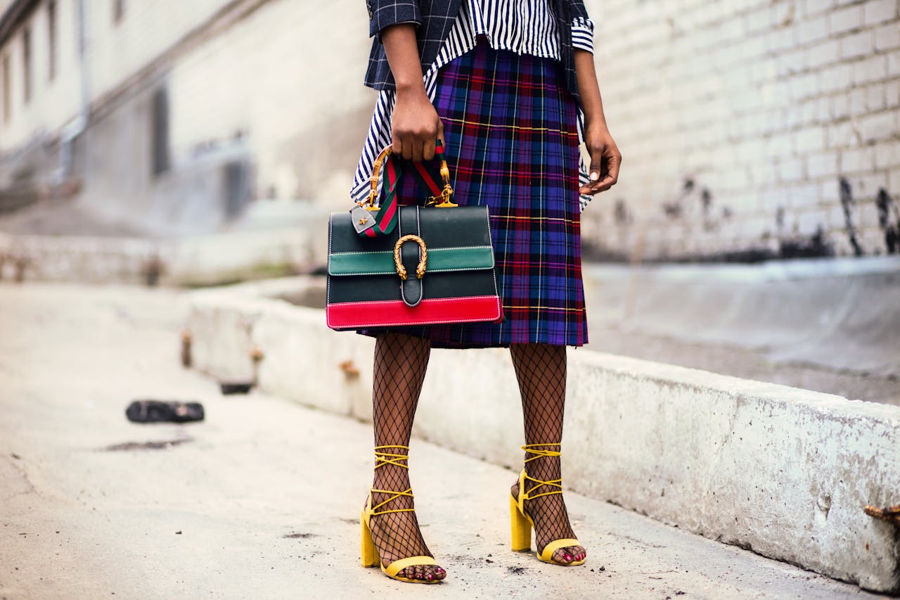 services-02 Fashion-forward outfit with plaid skirt and colorful handbag in urban setting.